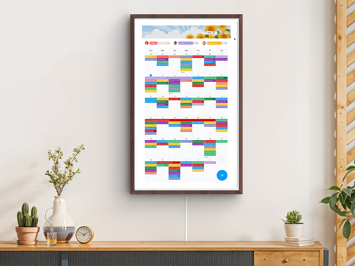 Vertical wall-mounted digital family calendar showing color-coded monthly schedule grid with multiple appointments and events for York's Family in wood frame