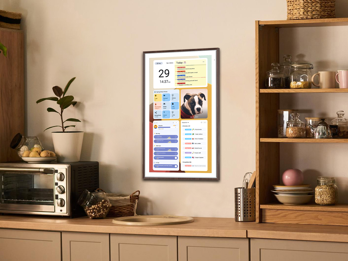 A digital calendar hangs on the kitchen wall, displaying a to-do list.