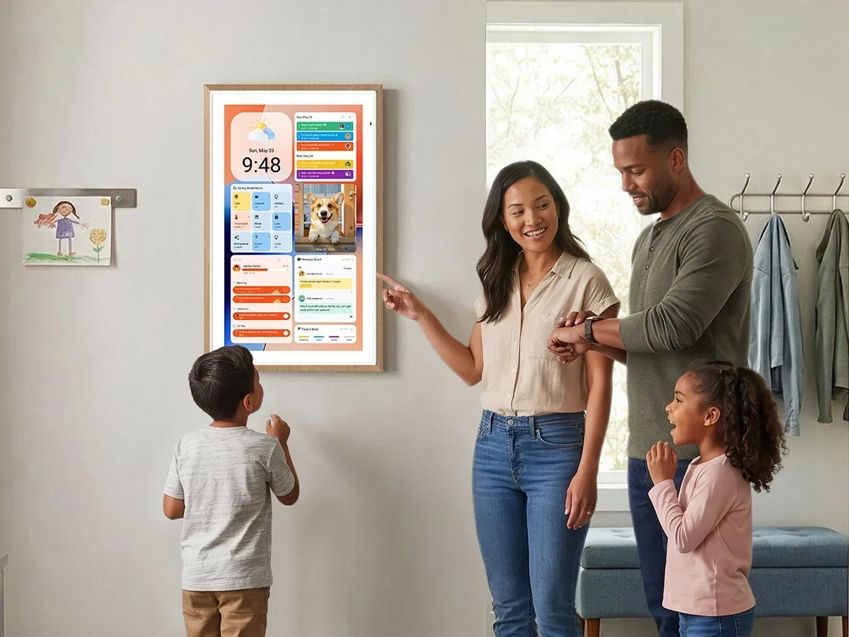 Mother points at wall-mounted digital calendar, father and two children watch excitedly in bright home